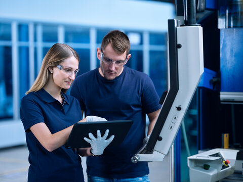 Workers wearing working on tablet PC by machine in industry