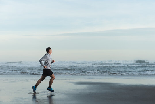 Hispanic teenager runner training at the beach.