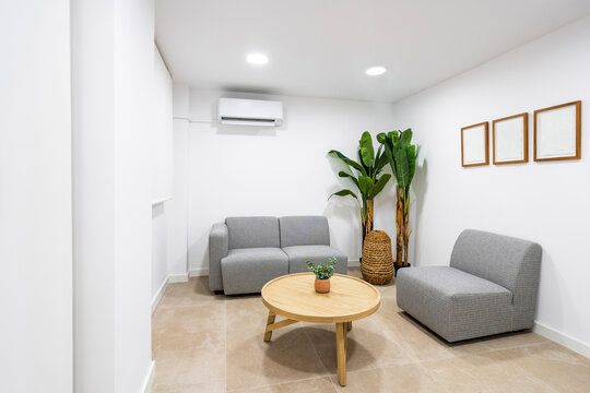 Table and sofa arranged in illuminated waiting room at clinic