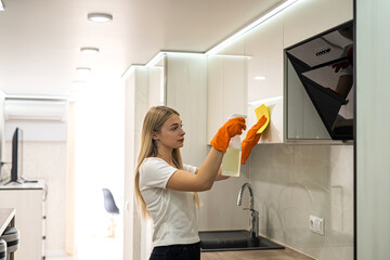  woman in glove with spray cleaning a surface of her kitchen