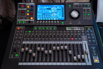 Modern digital mixing console with faders, control buttons and touch screen. Selective focus