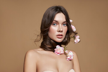 Portrait blonde woman in beige bodysuit and flowers in hair. Natural cosmetics and makeup. Romantic...