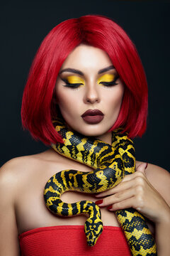 Beautiful woman with red hair and a yellow python snake around her neck. Professional Bright Beauty Eye Makeup Yellow, Red Burgundy Lipstick