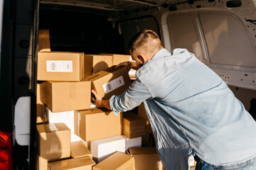 Young delivery man arranging packages in van