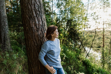Thoughtful woman leaning on tree
