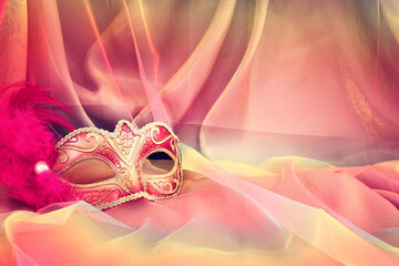 Photo of elegant and delicate pink Venetian mask over colorful chiffon background