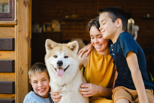 Smiling sons with mother and Akita dog outside house