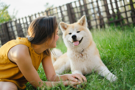 Playful woman looking at Akita dog siting on grass