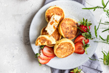 Cottage cheese pancakes or fritters with strawberry and natural yogurt. Healthy breakfast or lunch. Syrniki. Top view.