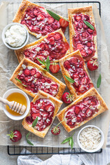 Delicious sweet sliced pies with strawberry. Puff pastry mini pies with strawberry, cream cheese, almond and honey. Top view.