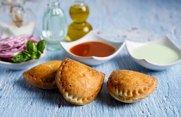 Homemade empanadas with sauces. South American street food. These delicious beef empanadas are mandatory to eat, they have a crunchy dough and an exquisite ground beef filling.