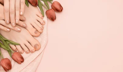 Poster Vrouwelijke handen met veernagelontwerp. Glitter beige nagellak pedicure. Vrouwelijke handen en voeten met tulp bloemen op roze achtergrond. Ruimte kopiëren. © devmarya
