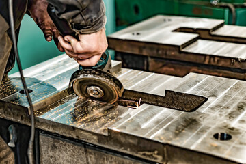 Grinding burrs and metal with an angle grinder with sparks.