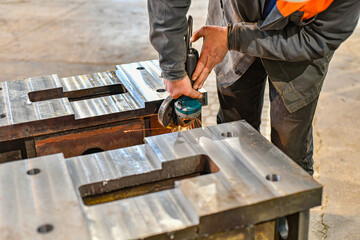 Grinding burrs and metal with an angle grinder with sparks.