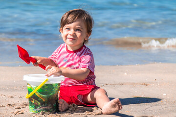 little boy playing with bucket and spade on the seashore on the beach