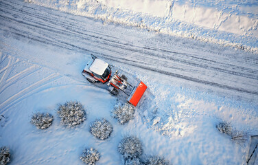 Snow removing with red tractor on the road. Suny winter day, Drone top view.