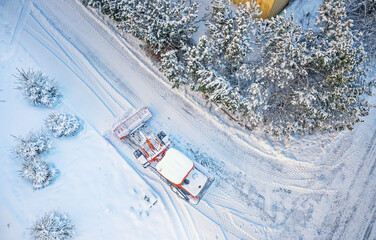 Snow removing with red tractor on the road. Suny winter day, Drone top view.