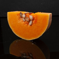 Calabaza cortada con semillas sobre fondo negro. Sliced ​​pumpkin with seeds on black...