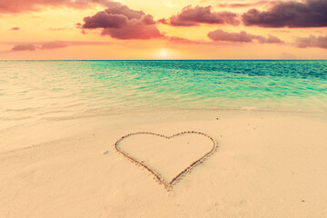 Obraz na płótnie Canvas Heart on sand on tropical beach at sunset.