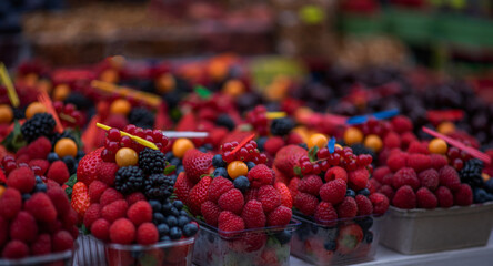 Blurred image of berries close-up colorful assorted strawberries, blueberries, raspberries, blackberries on the market counter. Juicy, ripe berries, ready to eat. Farming natural eco-products.