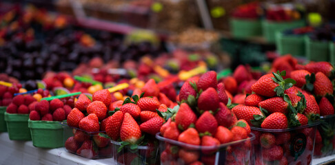 Blurred image of berries close-up colorful assorted strawberries, blueberries, raspberries, blackberries on the market counter. Juicy, ripe berries, ready to eat. Farming natural eco-products.