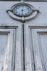 vintage and retro public city clock showing the time on the white wall ornament with low angle view