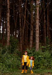 Adorable little siblings with red hair standing in fir woods