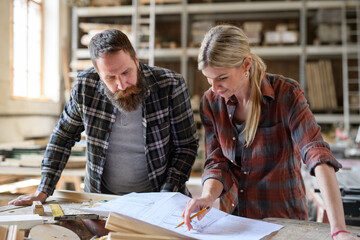 Two carpenters man and woman talking about design of products. Small business concept.
