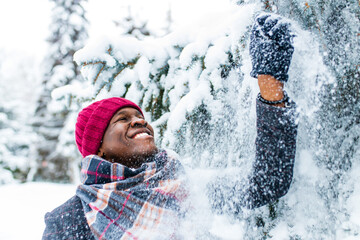 african american man in a snowy winter woodland with snowflakes falling from spruce and fir forest