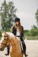 Obraz premium Portrait of woman in black helmet riding a brown horse