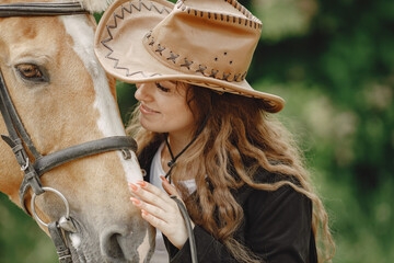 Portrait of woman in brown leather hat with a horse