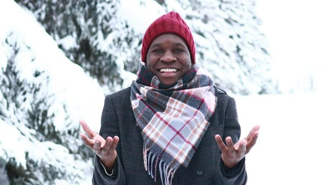 african american handsom man in red hat and stylish plaid coat look at camera with toothy snow- white smile and talking outdoor in park