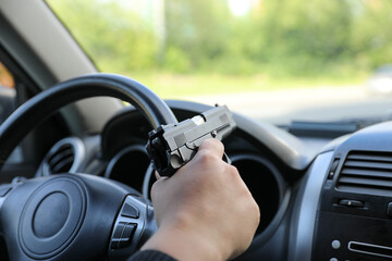 Man driving a car with a weapon, gun in his hand. The criminal steals the car. Danger district of...