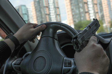 Man driving a car with a weapon, gun in his hand. The criminal steals the car. Danger district of the city