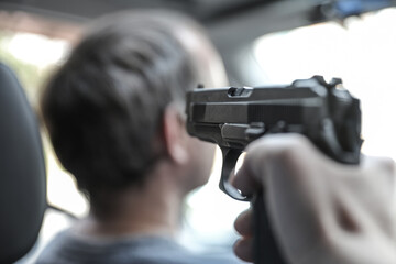 Selective focus. The offender aims at the driver of the car, theft, robbery, danger