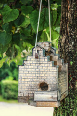 Birdhouse castle suspended on a tree. Unusual bird house made of wood.