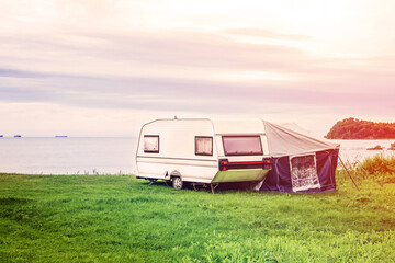 Trailer home and a tent by the grass lake shore. Adventure relaxing travel on caravan van and camping home - obrazy, fototapety, plakaty