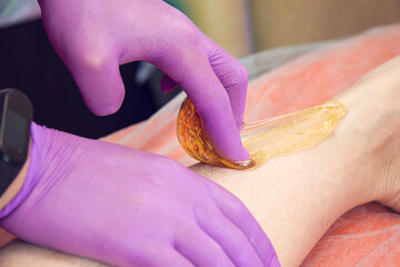 Leg hair removal procedure in a beauty salon. Sugar paste, shugaring, depilation