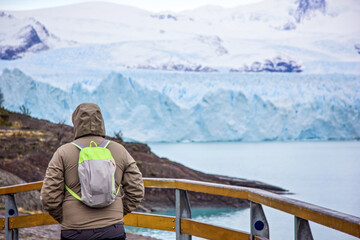 Fototapeta na wymiar Young man, guy looks at Perito Moreno glacier in Patagonia. Floe located in Los Glaciares National Park, in the southwest of the Argentine province of Santa Cruz, El Calafate