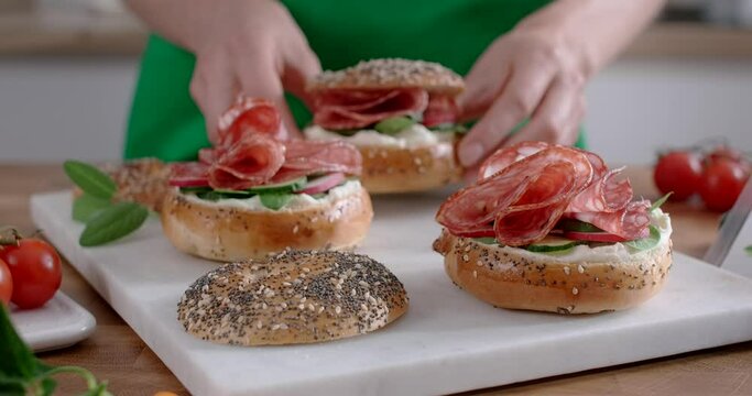 The cook makes bagles with pepperoni in slow motion. Making burgers with salami, 4k 60p Prores