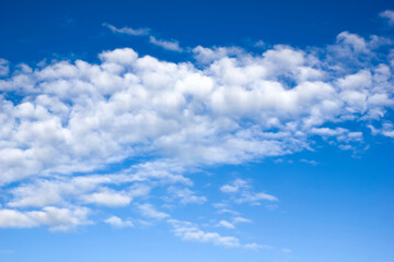 A strip of aerial volumetric clouds in clear weather against a blue sky.