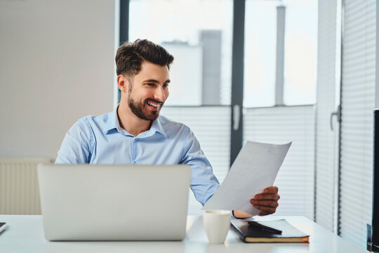 Happy businessman working by the desk looking on document