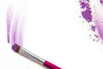 Violet eye shadow, crushed cosmetic isolated on white background with pink brush. A smashed, bright...
