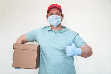 Fototapeta na wymiar Parcel delivery. Courier in gloves and a mask with a box for a customer. A man with a parcel in his hands.