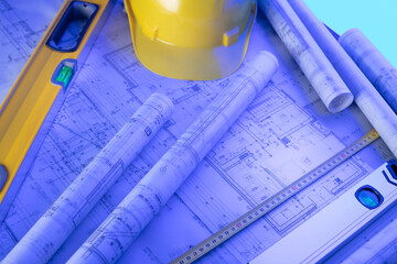 Contractor theme. Tool kit of the contractor: yellow hardhat, libella, hand saw. Plans and notebook on the desk.