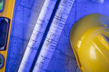 Contractor theme. Tool kit of the contractor: yellow hardhat, libella, hand saw. Plans and notebook on the desk.