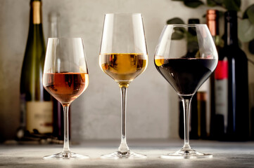 Wines assortment. Red, white, rose wine in glasses and bottles on gray table background. Wine bar, shop, tasting concept