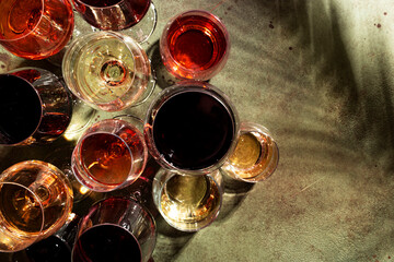 Red, white and rose wines in assortment in glasses on green background, top view. Wine bar, shop,...