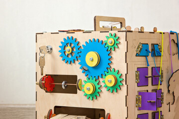 Handmade colored busy cube from plywood. Educational toy for children, game panel