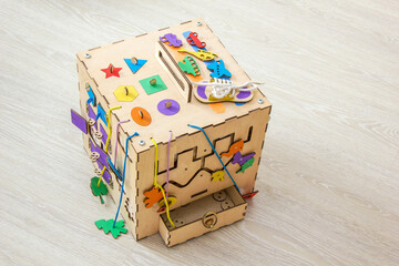 Handmade colored busy cube from plywood. Educational toy for children, game panel